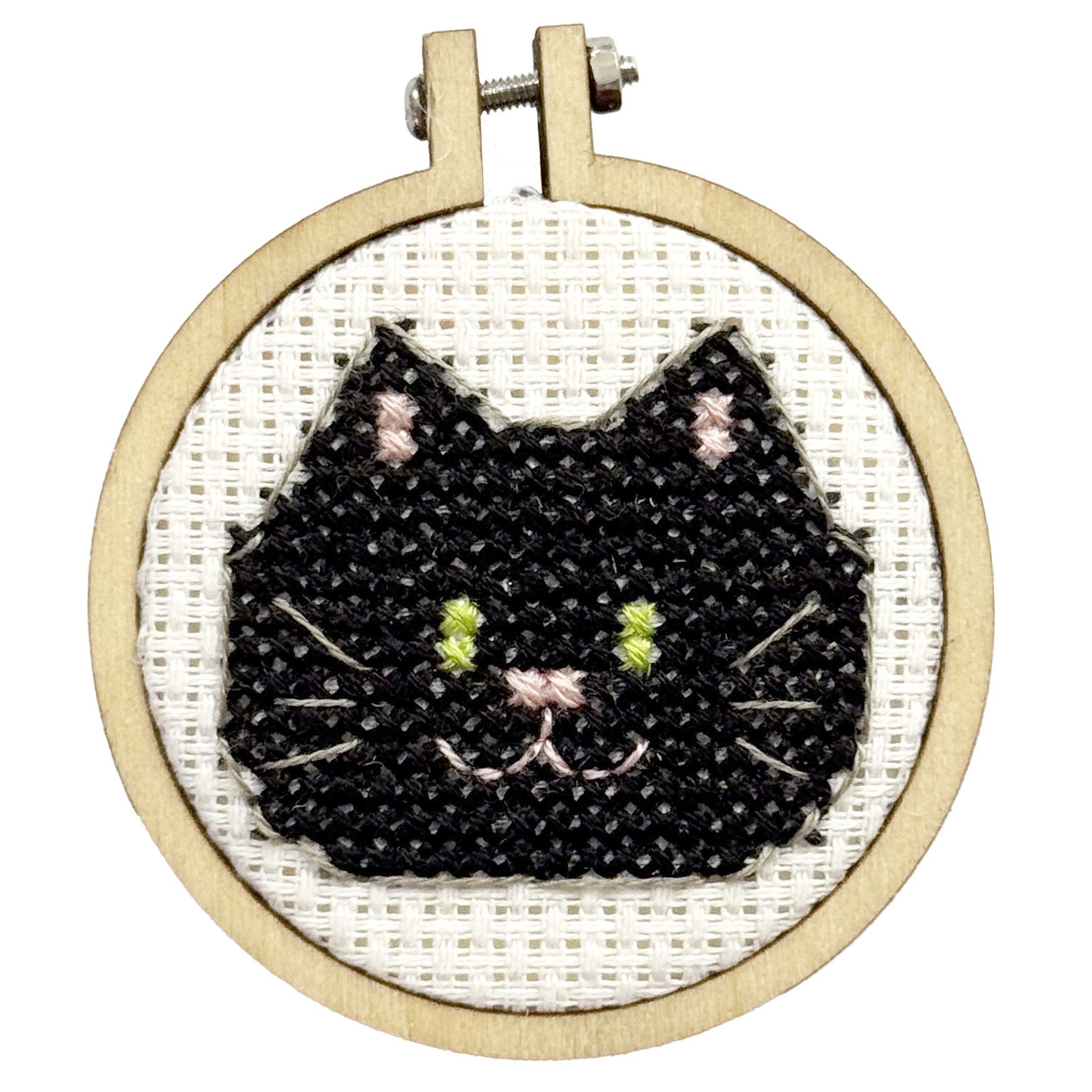 Embroidery hoop with a black cat face design on white fabric