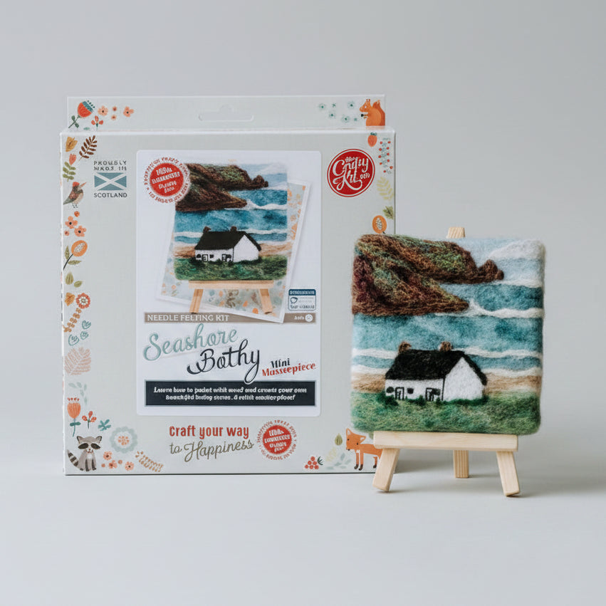 Craft kit packaging with a small needle felted artwork on an easel against a blurred background