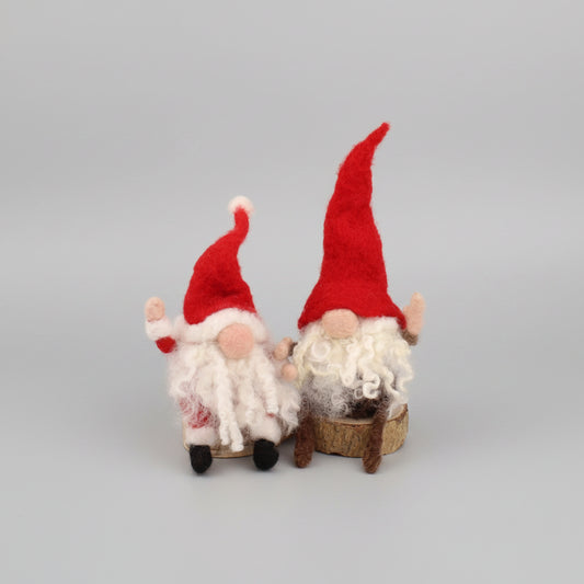 Two small felt gnome decorations with red pointed hats, white fluffy beards, and pink faces, standing side by side on a plain white background.