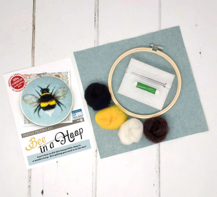 Needle felting kit with hoop, felt balls, and backing felt on a wooden surface