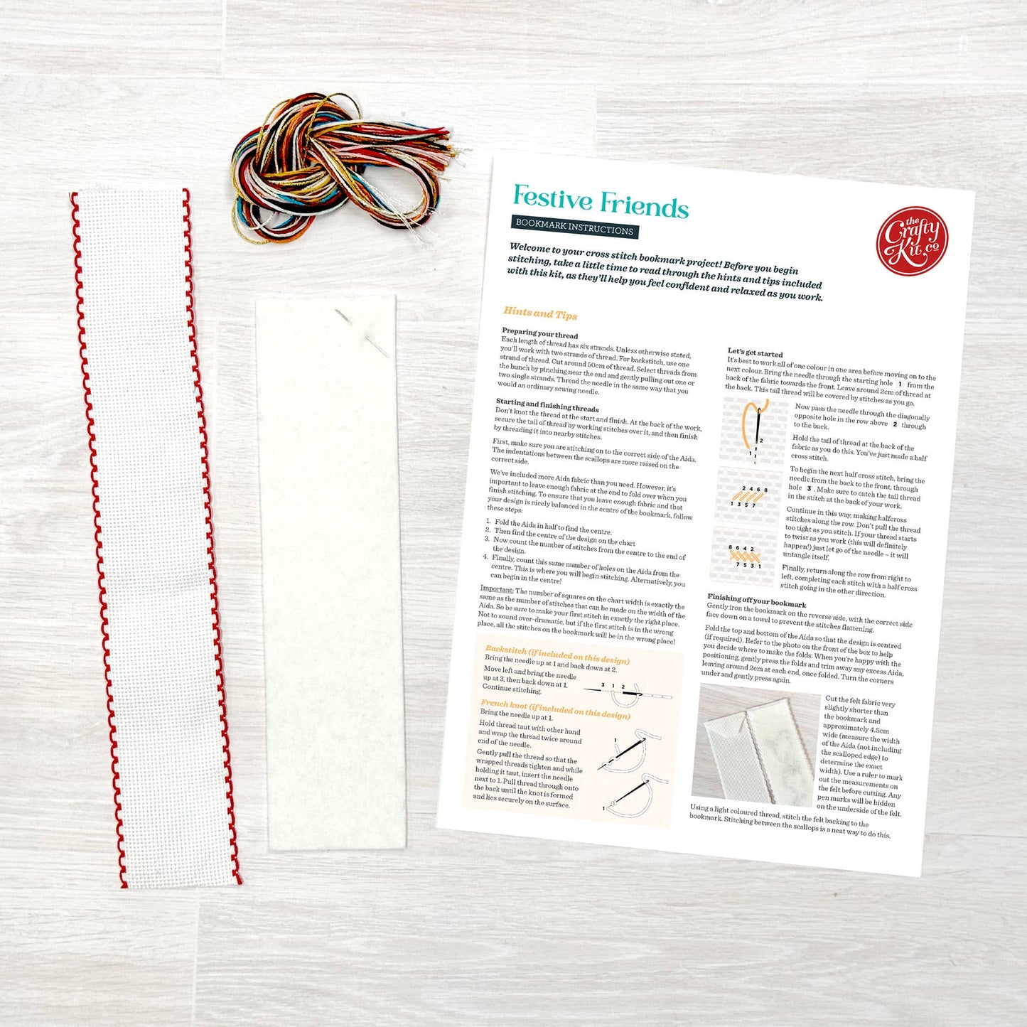 Colourful yarn, material strips and a pattern sheet on a wooden surface