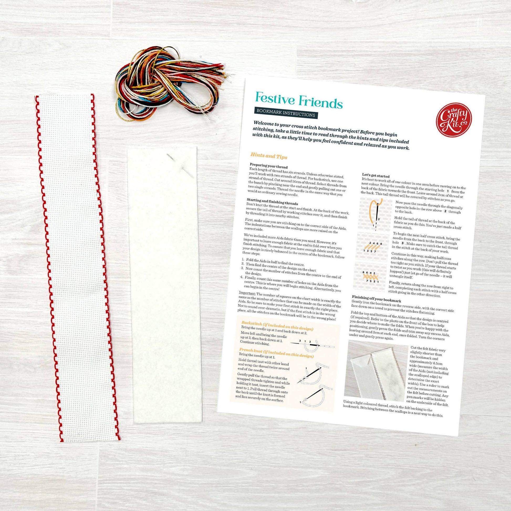 Colourful yarn, material strips and a pattern sheet on a wooden surface