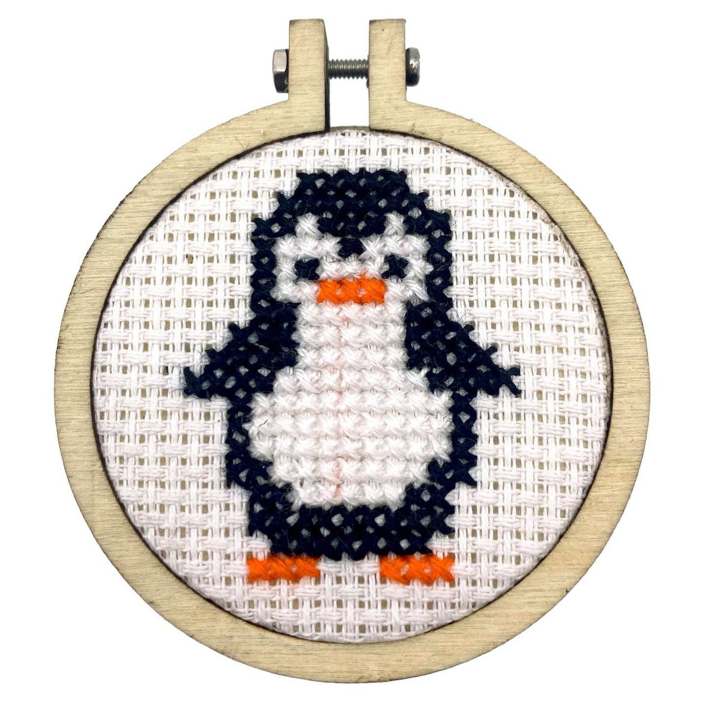 Cross-stitched penguin in an embroidery hoop on a white background