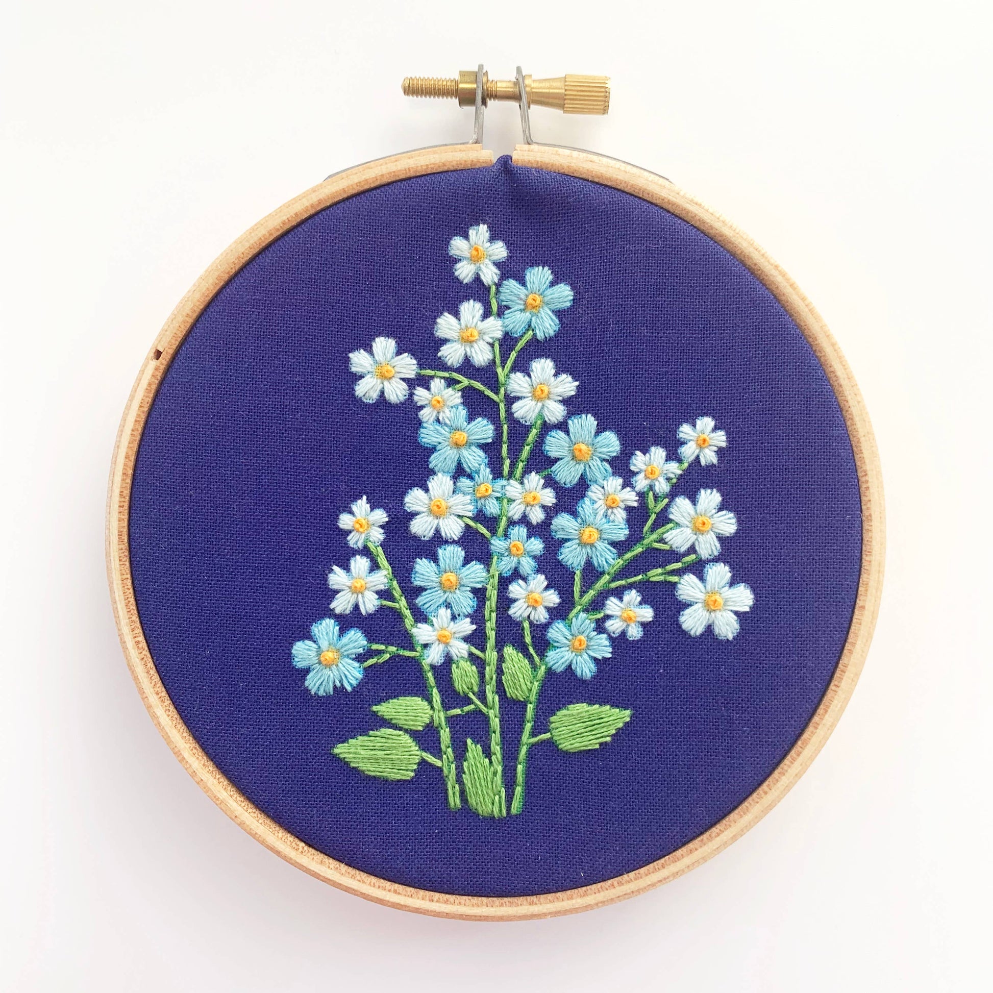 Embroidery hoop with floral design on a blue fabric background