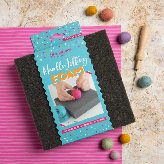 Hawthorn Needle Felting Foam with packaging on a pink mat, surrounded by felting tools and materials.