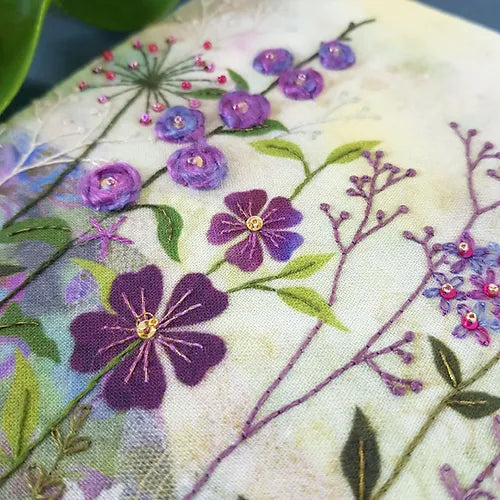 Close-up of embroidered flowers on fabric with a focus on purple and green details.