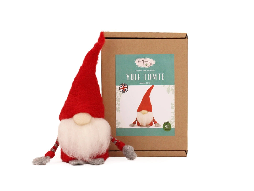 Red Tomte next to a cardboard box with a Yule Tomte design on a white background